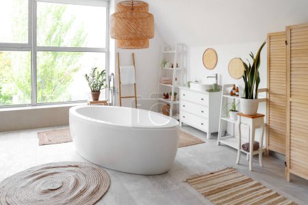 Téléchargez les photos : Intérieur de la salle de bain avec baignoire blanche, commode et plantes d'intérieur - en image libre de droit