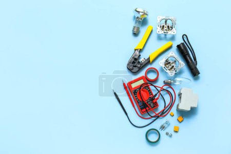 Electrician's tools, light bulb and electronics on blue background