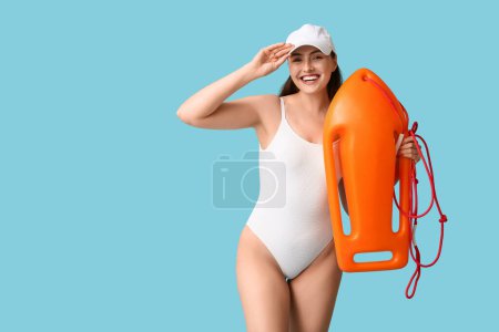 Photo for Young female lifeguard with rescue buoy on blue background - Royalty Free Image