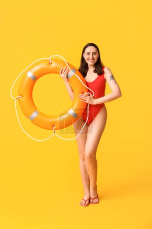 Photo for Young female lifeguard with ring buoy on yellow background - Royalty Free Image