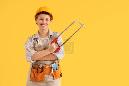 Téléchargez les photos : Jeune charpentier femelle avec scie à métaux sur fond jaune. Fête du travail - en image libre de droit