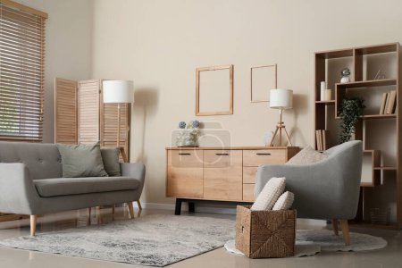 Téléchargez les photos : Intérieur du salon moderne avec commode en bois et fauteuils confortables près du mur beige - en image libre de droit