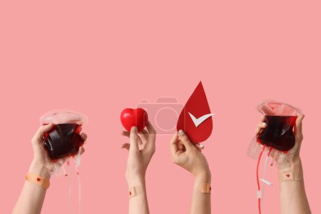 Blood donors with packs for transfusion, grip ball and paper drop on pink background