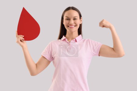 Female blood donor with paper drop showing muscles on light background
