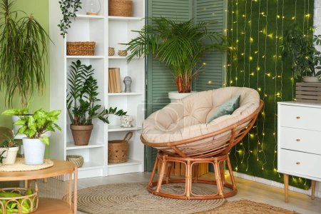 Téléchargez les photos : Intérieur du salon avec plantes vertes, fauteuil et lumières incandescentes - en image libre de droit