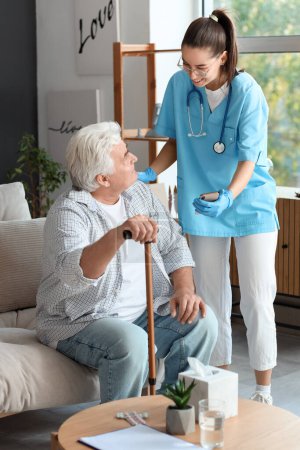 Krankenschwester zeigt Seniorin zu Hause Handy mit Stock