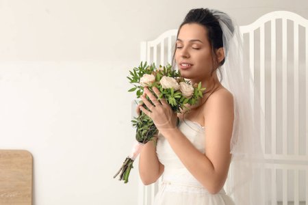 Foto de Novia joven con ramo de boda cerca de la pantalla plegable sobre fondo claro - Imagen libre de derechos