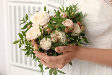 Téléchargez les photos : Jeune mariée avec bouquet de mariage près de l'écran pliant sur fond clair, gros plan - en image libre de droit