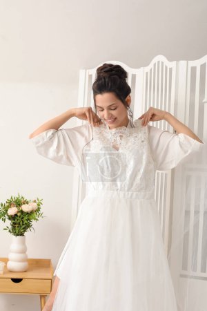 Foto de Joven novia probándose su vestido de novia en el dormitorio - Imagen libre de derechos