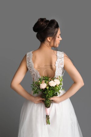 Foto de Hermosa novia joven con ramo de boda sobre fondo oscuro, vista trasera - Imagen libre de derechos