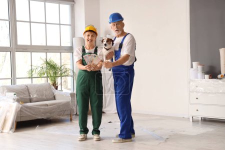 Photo for Mature couple of decorators with paint color palettes and dog during repair in room - Royalty Free Image