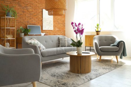 Interior of living room with sofa, armchairs and orchid flower on table