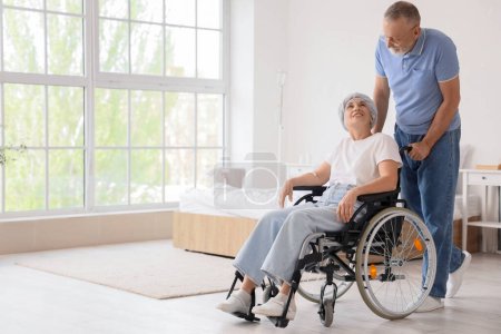 Reife Frau nach Chemotherapie im Rollstuhl mit Ehemann zu Hause