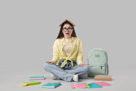 Photo for Female student with books sitting on light background - Royalty Free Image