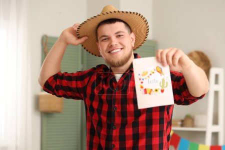 Happy young man with greeting card at home. Festa Junina celebration