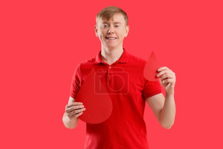 Male blood donor with paper drops on red background