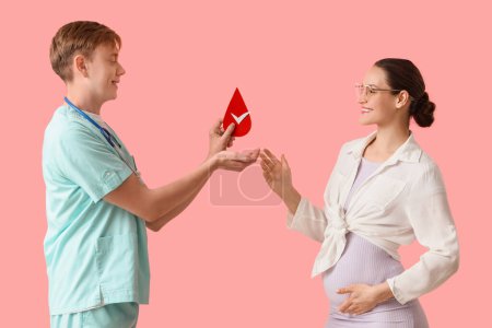 Männliche Krankenschwester gibt schwangeren Frau Bluttropfen auf rosa Hintergrund