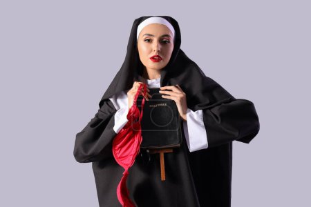 Sexy Nonne mit BH und Bibel auf hellem Hintergrund