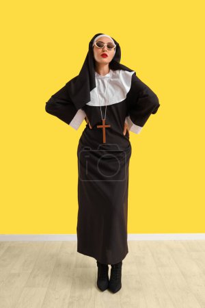 Photo for Naughty nun in sunglasses near yellow wall - Royalty Free Image