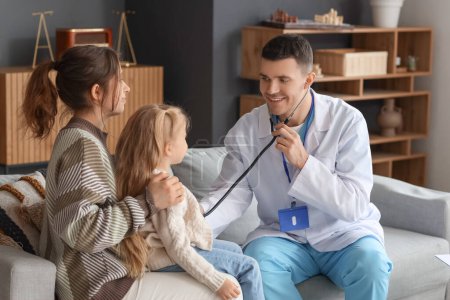 Male pediatrician with stethoscope examining little girl sitting on mother's lap at home