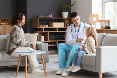 Male pediatrician with little girl with tongue depressor at home