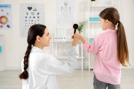 Female ophthalmologist with occluder and little girl in clinic
