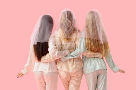 Young woman and her bridesmaids in pajamas hugging on pink background, back view. Hen Party