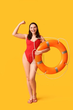 Photo for Female lifeguard with ring buoy showing muscles on yellow background - Royalty Free Image