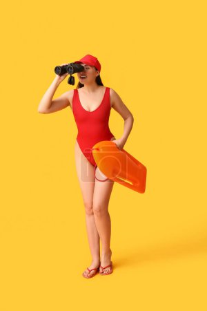Photo for Female lifeguard with rescue buoy and binoculars on yellow background - Royalty Free Image