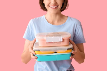 Beautiful young happy woman with lunchboxes of tasty food on pink background, closeup
