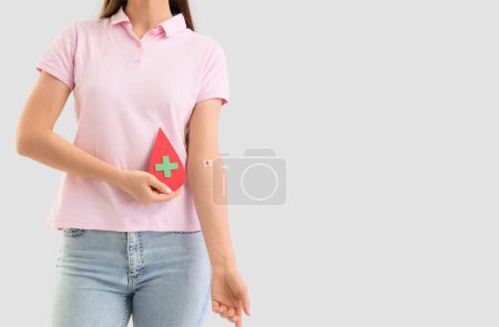 Female blood donor with applied patch and paper drop on light background