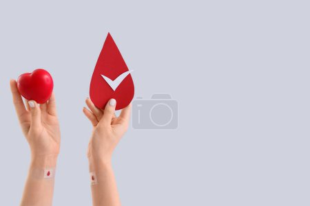 Female blood donor with grip ball and paper drop on light background