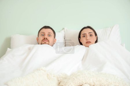 Téléchargez les photos : Shocked young man with his mistress lying in bed. Cheating concept - en image libre de droit