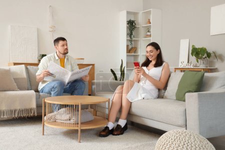 Téléchargez les photos : Young woman texting lover and her husband at home. Cheating concept - en image libre de droit