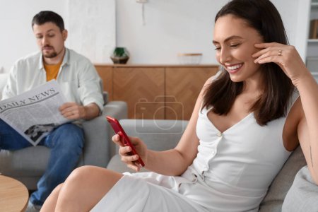 Téléchargez les photos : Young woman texting lover and her husband at home. Cheating concept - en image libre de droit