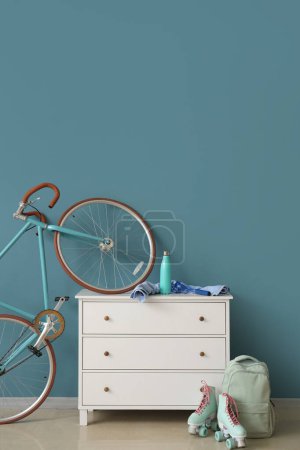 Schrank mit Fahrrad, Rollschuhen und Rucksack nahe blauer Wand