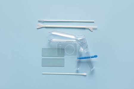 Gynäkologisches Spekulum mit Pap-Abstrichprüfgeräten auf blauem Hintergrund
