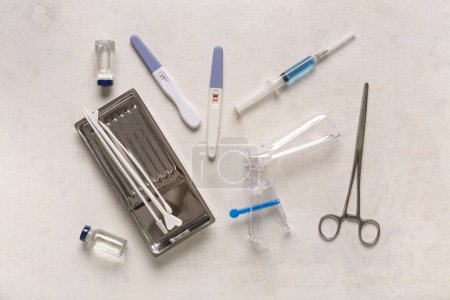 Gynäkologisches Spekulum mit Pap-Abstrichwerkzeugen, Schwangerschaftstests und Ampullen auf weißem Grunge-Hintergrund