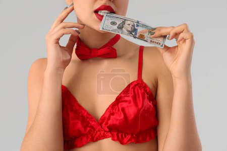 Young prostitute with dollar banknotes on light background, closeup. Sex for money concept