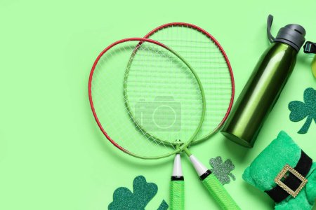 Photo for Badminton rackets, water bottle, clovers and leprechaun's hat on green background. St. Patrick's Day celebration - Royalty Free Image