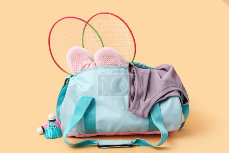 Photo for Sports bag with sportswear, badminton rackets and shoes on beige background - Royalty Free Image