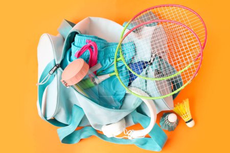 Photo for Sport bag, badminton rackets, headphones and water bottle on orange background - Royalty Free Image