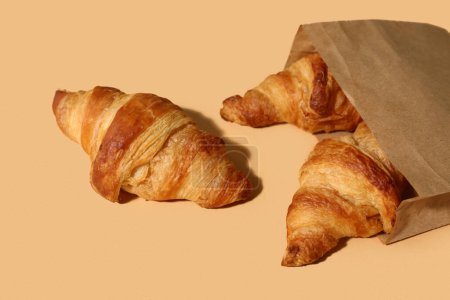 Foto de Bolsa de papel con sabrosos croissants sobre fondo marrón - Imagen libre de derechos