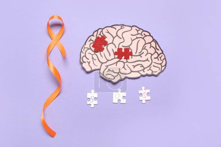 Paper brain with puzzle pieces and orange ribbon on lilac background. Multiple Sclerosis Awareness Month
