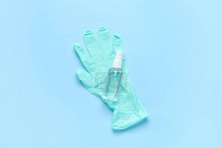 Gummihandschuhe mit Flasche Desinfektionsmittel auf blauem Hintergrund