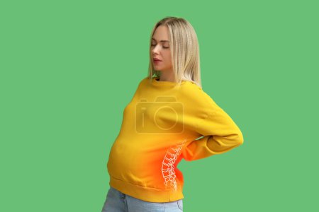 Schwangere spüren Schmerzen in der Wirbelsäule auf grünem Hintergrund