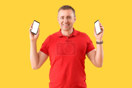 Mature man with mobile phones on yellow background