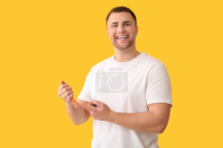 Schöner junger glücklicher Diabetiker mit Spitzstift auf gelbem Hintergrund
