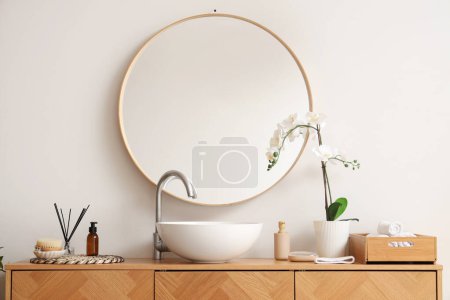 Wooden cabinet with sink, mirror and bathing accessories in stylish bathroom