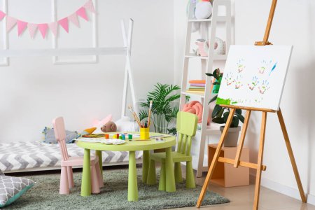 Interior of children's bedroom with easel and paints on table